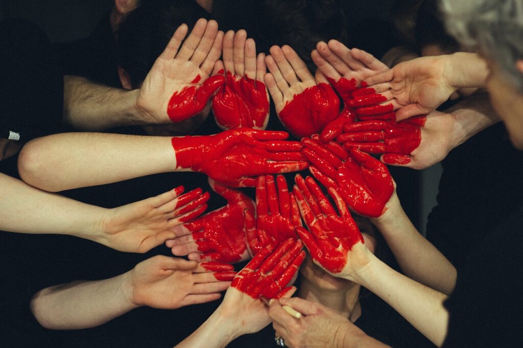 Photo de plusieurs main assemblées paumes vers l'objectif sur lesquelles un coeur rouge est dessiné